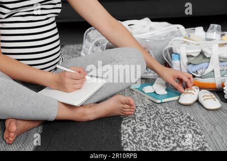 Donna incinta sacchetto di imballaggio per l'ospedale di maternità a casa, primo piano Foto Stock