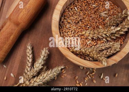 Mortaio, pestello e spighe di grano su tavola di legno, piatto Foto Stock