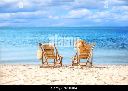 Lettini in legno vuoti sulla spiaggia di sabbia vicino al mare nelle giornate di sole Foto Stock