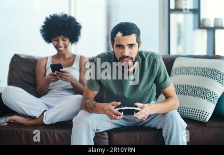 Ci piace avere tempo da fare ora e poi. una donna che usa il cellulare mentre il suo ragazzo gioca ai videogiochi. Foto Stock