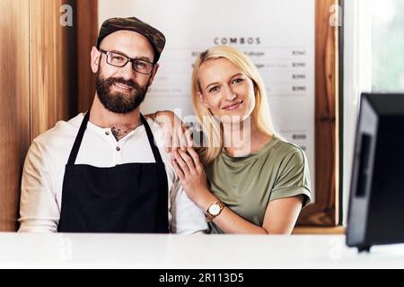 Beh, ti stai guardando al meglio in un istante. Ritratto di un giovane barbiere felice e parrucchiere in posa insieme all'interno del loro salone. Foto Stock