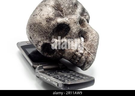 vecchio cellulare e cranio di metallo, parlare al telefono e la guida è pericoloso Foto Stock