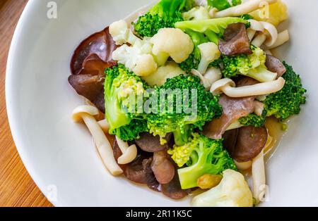 Menu di cibi salutari, funghi fritti in primo piano, cavolfiore e broccoli, cibo di verdure misto tailandese sano su un piatto bianco. Immagine ravvicinata, vista fr Foto Stock