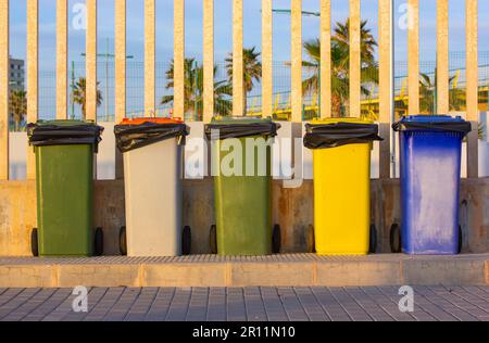 Bidoni multicolore per la raccolta di rifiuti in metallo per la raccolta di diversi tipi di rifiuti su una strada cittadina. Row, gruppo di molti rifiuti dumster all'aperto. Rifiuti ecologici con Foto Stock