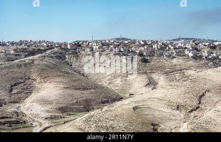 L'antica città palestinese di al-Azariya si trova di fronte alle torri di Gerusalemme est e dietro le colline desertiche con un cielo blu Foto Stock