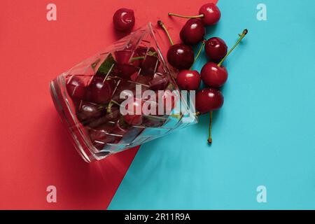 ciliegie mature in un bicchiere su fondo rosso Foto Stock