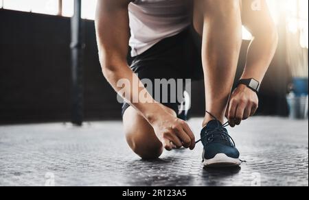 Metti il tuo piede migliore in avanti nel gioco di fitness. un uomo che legava le scarpe in palestra. Foto Stock