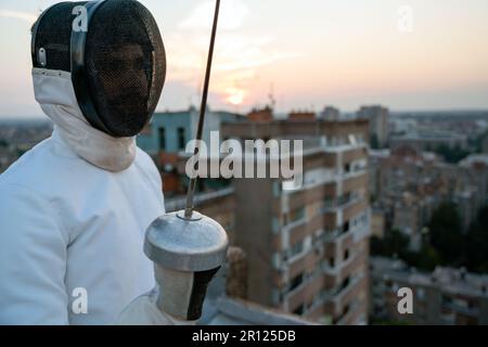 Donna in costume da scherma bianco che pratica all'aperto. Sport, allenatore professionale, stile di vita sano. Foto Stock