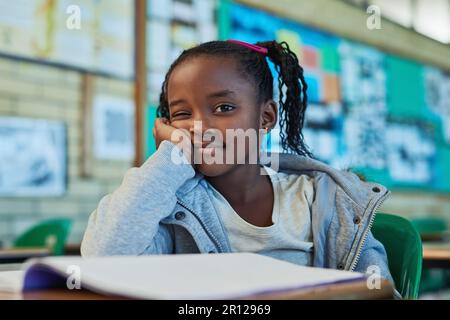 Mi chiedo di cosa si possa imparare oggi. Ritratto di una bambina di scuola elementare che lavora in classe. Foto Stock