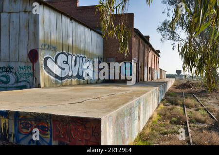 Un percorso ferroviario con mattoni e pareti ricoperti di graffiti, che illustra la vivace cultura della Street art della zona Foto Stock