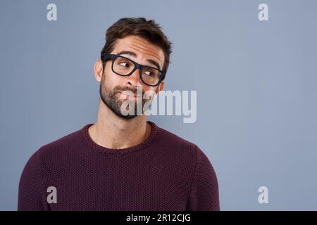 Se lo dici. Studio shot di un bel giovane che guarda scettico su uno sfondo grigio. Foto Stock