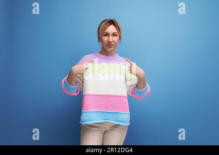 la ragazza bionda si mostra le mani su uno sfondo blu Foto Stock