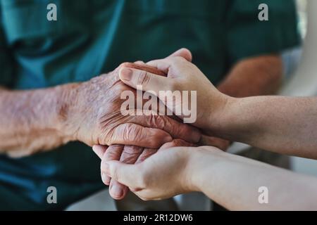 La gentilezza inizia con voi. Primo piano di una donna che tiene le mani di un uomo anziano in comodità. Foto Stock