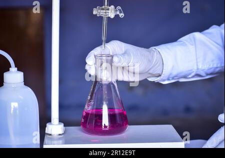 Lo scienziato sta effettuando una titolazione acido-base in laboratorio, misurando con precisione la quantità di acido o base necessaria per neutralizzare una soluzione. Accurat Foto Stock