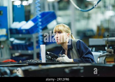 Nizhny Novgorod, Russia - 21 novembre 2020: Stabilimento di produzione auto DI GAZ. Giovane donna bionda operatrice. Foto Stock
