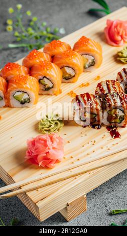 Un pannello di legno che mostra una varietà di sushi rotoli in colori e dimensioni assortite Foto Stock