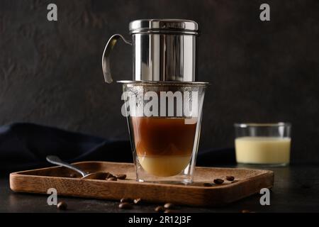 Cucina tradizionale vietnamita con latte condensato in tazza di vetro su sfondo nero. Primo piano. Foto Stock