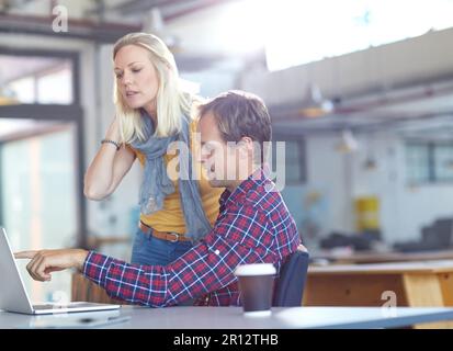 Mettere le idee in azione. due designer che lavorano su un notebook in ufficio. Foto Stock