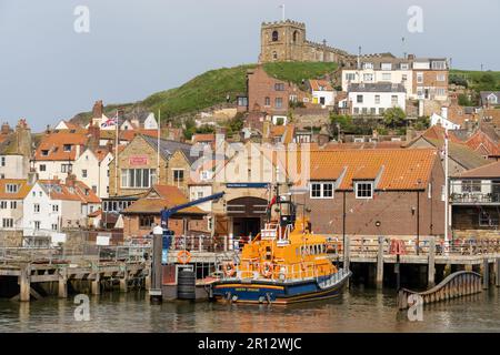 RNLI Whitby Lifeboat Station a Whitby, North Yorkshire, Regno Unito, con la scialuppa di salvataggio ormeggiata all'esterno. Foto Stock