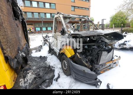 11 maggio 2023, Amburgo: Diversi furgoni di consegna bruciati si trovano nel parcheggio di un centro di distribuzione della posta ad Amburgo-Altona, Germania, che ha preso fuoco giovedì sera. La schiuma antincendio bianca può essere vista dall'operazione antincendio. Tre furgoni erano a fuoco pieno, due dei quali erano veicoli elettrici che il reparto antincendio doveva lasciare bruciare in modo controllato perché le loro batterie erano danneggiate, secondo un portavoce del reparto antincendio di Amburgo. La causa dell'incendio era inizialmente poco chiara. Tuttavia, una portavoce della polizia ha affermato che erano in corso indagini su sospetti Foto Stock