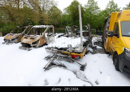 11 maggio 2023, Amburgo: Diversi furgoni di consegna bruciati si trovano nel parcheggio di un centro di distribuzione della posta ad Amburgo-Altona, Germania, che ha preso fuoco giovedì sera. La schiuma antincendio bianca può essere vista dall'operazione antincendio. Tre furgoni erano a fuoco pieno, due dei quali erano veicoli elettrici che il reparto antincendio doveva lasciare bruciare in modo controllato perché le loro batterie erano danneggiate, secondo un portavoce del reparto antincendio di Amburgo. La causa dell'incendio era inizialmente poco chiara. Tuttavia, una portavoce della polizia ha affermato che erano in corso indagini su sospetti Foto Stock