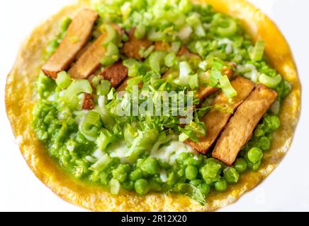 Omelette all'uovo con purè di piselli freschi verdi e gambo di sedano e tofu affumicato su piatto bianco, primo piano. Foto Stock