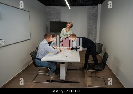 L'estrusione femminile valuta il lavoro dei subordinati. Progettisti ingegneri a una riunione. Foto Stock
