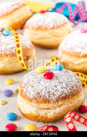 Ciambelle a base di zucchero a velo di carnevale con streamers di carta, confetti e fagioli di cioccolato, verticali Foto Stock