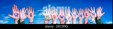 Bambini mani costruire parola Wir Gewinnen significa vincere. Cielo blu Foto Stock