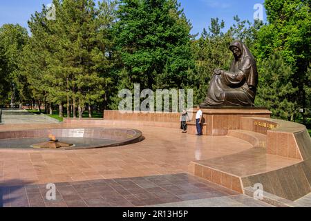 una coppia uzbeka posa insieme di fronte alla fiamma eterna di fronte al monumento della madre che piange per onorare i soldati nella seconda guerra mondiale Foto Stock