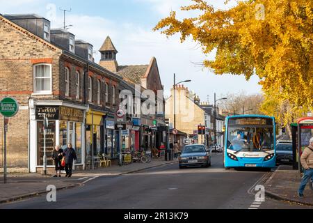 Autunno su Mill Road Broadway, Cambridge, Regno Unito. Un autobus si trova a una fermata accanto ad una sfilata di piccoli negozi indipendenti. Foto Stock