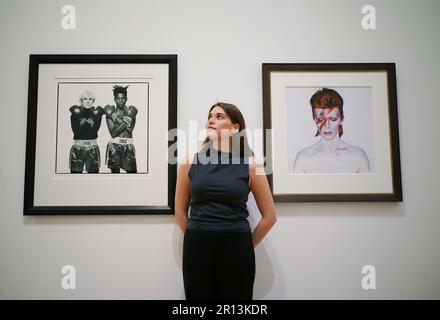 Un membro del personale della galleria posa accanto alle fotografie di (a sinistra) Michael Halsband, Andy Warhol + Jean-Michel Basquiat #143, New York City, 10th luglio 1985, con una stima di £20.000-30.000, E Brian Duffy, David Bowie, 1973 anni, con una stima di £ 7.000-9.000, in mostra a Phillips, Londra, durante una telefonata fotografica per una collezione privata di opere di fotografi del 20th e del 21st ° secolo, prima di essere offerti per la vendita dalla casa d'aste. Data immagine: Giovedì 11 maggio 2023. Foto Stock