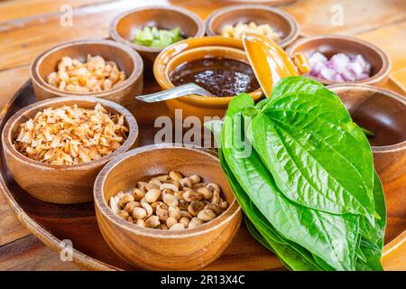 Grande piatto di molti ingredienti freschi con foglie di betel verde chiamato Miang Kham, il tradizionale cibo tailandese antipasto da avvolgere gli ingredienti Foto Stock