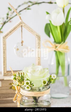 Decorazione floreale primaverile con rosa bianca, rami di ciliegio, giacinto e uccello di legno, verticale Foto Stock
