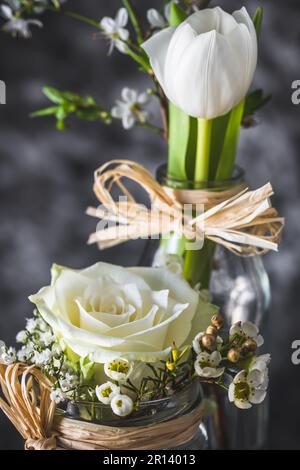 Decorazione floreale primaverile con rosa bianca e tulipano su sfondo grigio, verticale Foto Stock