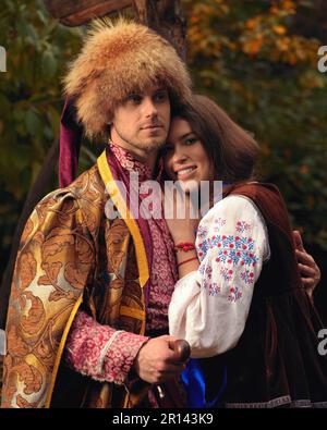 Giovane coppia felice vestito tradizionale ucraino vestiti. Uomo serio cossack e donna sorridente in costumi ricamati all'aperto. Vestito vintage Foto Stock