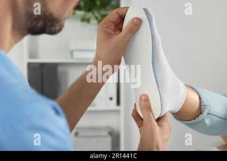 Soletta ortopedica maschile che si adatta al piede del paziente in ospedale, primo piano Foto Stock