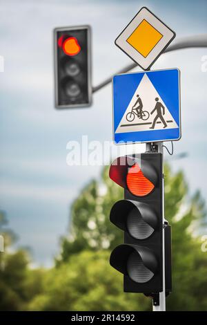 Posta con le indicazioni stradali Priority Road e Pedestrian, vicino al semaforo all'aperto Foto Stock