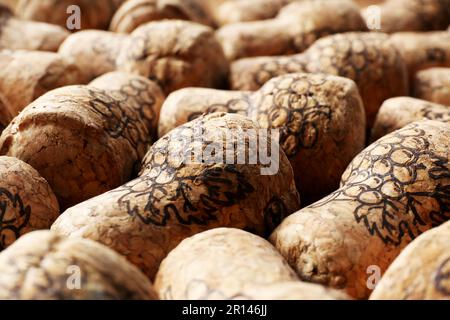 Molti tappi di bottiglie di vino con immagini di uva come sfondo, primo piano Foto Stock