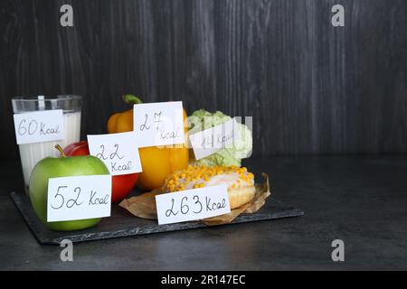 Prodotti alimentari con etichette del valore calorifico su tabella nera, spazio per testo. Concetto di perdita del peso Foto Stock