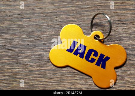 Cartellino in metallo giallo a forma di osso su tavolo in legno, primo piano. Spazio per il testo Foto Stock