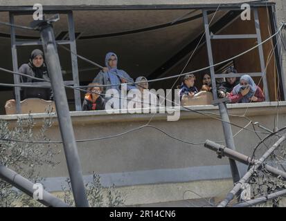 Gaza, Palestina. 11th maggio, 2023. I palestinesi guardano fuori dalla finestra della loro casa distrutta vicino alla casa del membro islamico della Jihad Anas al-Masri dopo gli attacchi aerei israeliani nella città di Beit Lahiya, nella striscia di Gaza settentrionale. I militanti palestinesi a Gaza hanno lanciato razzi verso Israele, dopo che i militari israeliani hanno effettuato una serie di attacchi aerei sui lanciarazzi della Jihad islamica. Credit: SOPA Images Limited/Alamy Live News Foto Stock