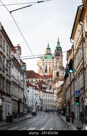 PRAGA, REPUBBLICA CECA - 24 AGOSTO 2022: Strada stretta nel quartiere di Mala Strana a Praga con la Chiesa di San Nicola che emerge sullo sfondo. Foto Stock