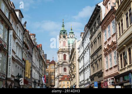 PRAGA, REPUBBLICA CECA - 25 AGOSTO 2022: Strada stretta nel quartiere di Mala Strana a Praga con la Chiesa di San Nicola che emerge sullo sfondo. Foto Stock