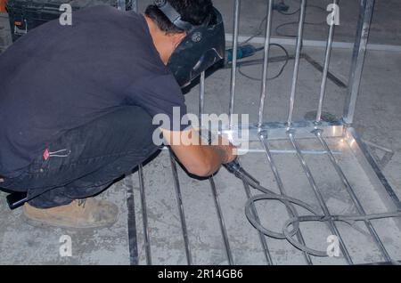 Fotografia di un lavoratore che salda una gabbia in un negozio di saldatura a Miami. Foto Stock