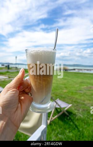 Bere latte macchiato caffee al lago Balaton in Ungheria sulla spiaggia. Foto Stock