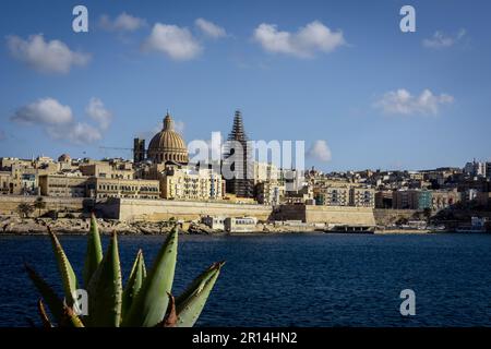 Valletta, Malta - 18 aprile 2023: Un panorama della città vecchia la Valletta, visto da Sliema. Verde agave pianta in primo piano. Foto Stock