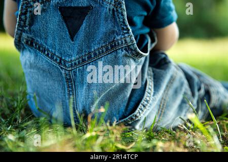 baby toddler in jeans blu tute in erba per godersi il caldo clima estivo Foto Stock