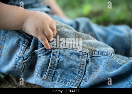 bambino toddler che indossa jeans sporchi dopo aver giocato nello sporco, senza volto Foto Stock