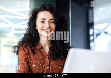 Primo piano ritratto di felice successo businesswoman, con capelli ricci sorridendo e guardando la macchina fotografica, donna matura capo che lavora in ufficio sul posto di lavoro soddisfatto con risultati di realizzazione. Foto Stock